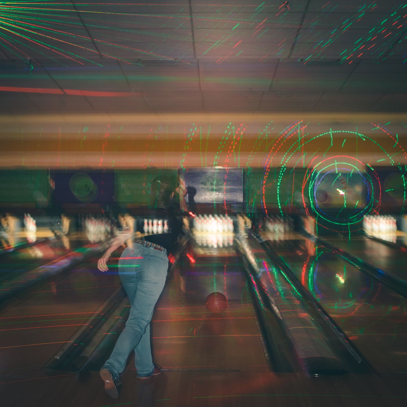 Speler gooit een bal op een neonverlichte bowlingbaan