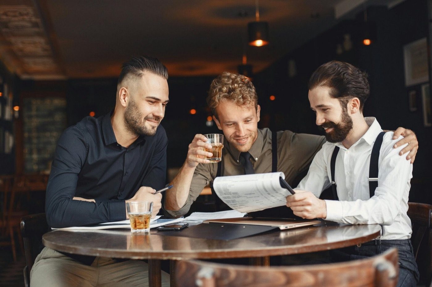 Gezelschap aan tafel in het café met drankjes en papieren